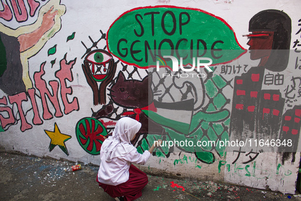 Students paint a mural to support the Palestinian people on a wall in the Liogenteng settlement area in Bandung, West Java, Indonesia, on Oc...