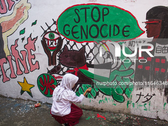 Students paint a mural to support the Palestinian people on a wall in the Liogenteng settlement area in Bandung, West Java, Indonesia, on Oc...