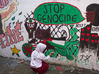 Students paint a mural to support the Palestinian people on a wall in the Liogenteng settlement area in Bandung, West Java, Indonesia, on Oc...