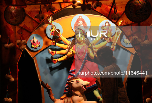 A Hindu senior citizen woman from an old age home offers prayer in front of an idol of the Hindu goddess Durga inside a tram compartment con...