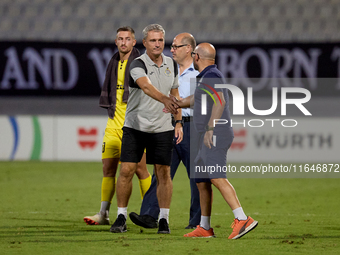 In Ta' Qali, Malta, on October 2, 2024, Branko Nisevic, head coach of Hibernians, shakes hands with Hamrun Spartans assistant coach Alessand...