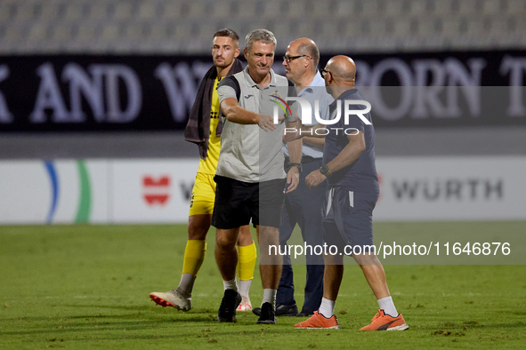 In Ta' Qali, Malta, on October 2, 2024, Branko Nisevic, head coach of Hibernians, shakes hands with Hamrun Spartans assistant coach Alessand...