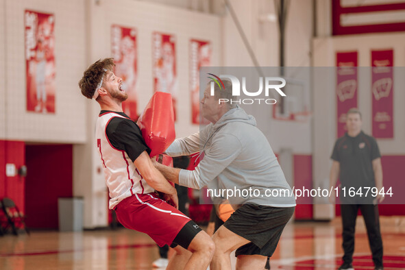 Wisconsin Badgers Associate Head Coach Joe Krabbenhoft hits forward Carter Gilmore #7 during a drill at the Nicholas Johnson Pavilion in Mad...