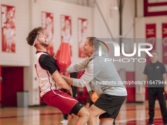 Wisconsin Badgers Associate Head Coach Joe Krabbenhoft hits forward Carter Gilmore #7 during a drill at the Nicholas Johnson Pavilion in Mad...