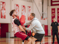 Wisconsin Badgers Associate Head Coach Joe Krabbenhoft hits forward Carter Gilmore #7 during a drill at the Nicholas Johnson Pavilion in Mad...