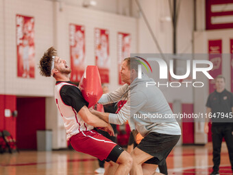 Wisconsin Badgers Associate Head Coach Joe Krabbenhoft hits forward Carter Gilmore #7 during a drill at the Nicholas Johnson Pavilion in Mad...