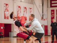 Wisconsin Badgers Associate Head Coach Joe Krabbenhoft hits forward Carter Gilmore #7 during a drill at the Nicholas Johnson Pavilion in Mad...