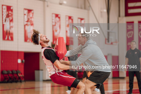 Wisconsin Badgers Associate Head Coach Joe Krabbenhoft hits forward Carter Gilmore #7 during a drill at the Nicholas Johnson Pavilion in Mad...