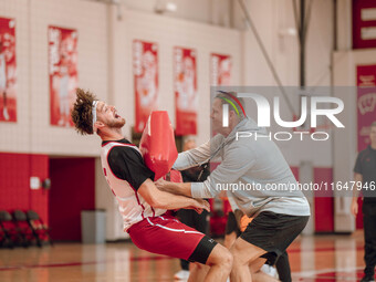 Wisconsin Badgers Associate Head Coach Joe Krabbenhoft hits forward Carter Gilmore #7 during a drill at the Nicholas Johnson Pavilion in Mad...