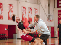 Wisconsin Badgers Associate Head Coach Joe Krabbenhoft hits forward Carter Gilmore #7 during a drill at the Nicholas Johnson Pavilion in Mad...