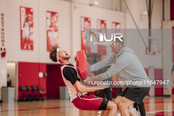 Wisconsin Badgers Associate Head Coach Joe Krabbenhoft hits forward Carter Gilmore #7 during a drill at the Nicholas Johnson Pavilion in Mad...