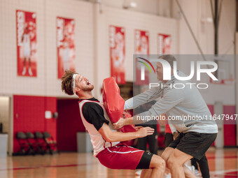 Wisconsin Badgers Associate Head Coach Joe Krabbenhoft hits forward Carter Gilmore #7 during a drill at the Nicholas Johnson Pavilion in Mad...