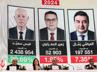 Members of the Tunisian election commission attend a press conference to announce the preliminary results of the presidential election, whil...