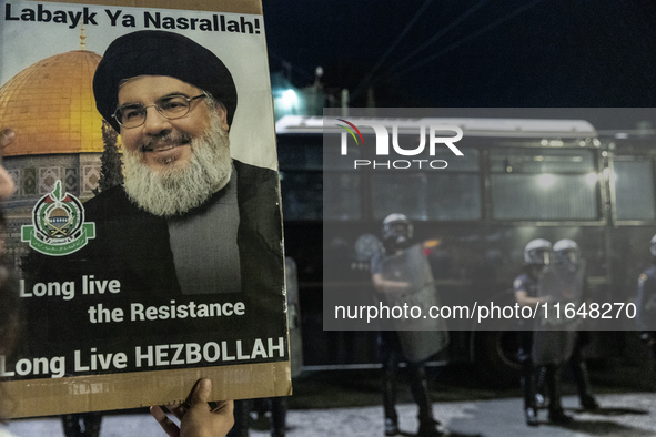 A man holds a sign with a picture of Hezbollah's deceased leader, Nasrallah, outside the Israeli Embassy in Athens, Greece, on October 7, 20...