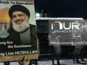 A man holds a sign with a picture of Hezbollah's deceased leader, Nasrallah, outside the Israeli Embassy in Athens, Greece, on October 7, 20...