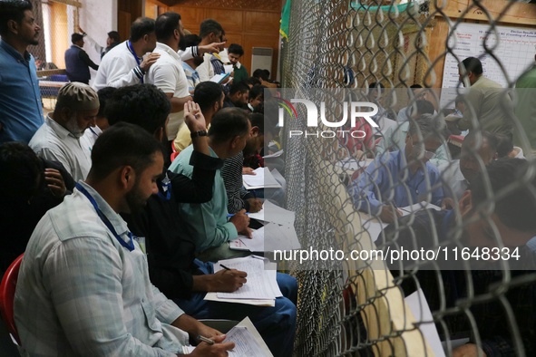 Political party representatives watch as election officials count votes for the local assembly elections at a counting center in Srinagar, J...