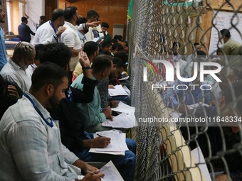 Political party representatives watch as election officials count votes for the local assembly elections at a counting center in Srinagar, J...