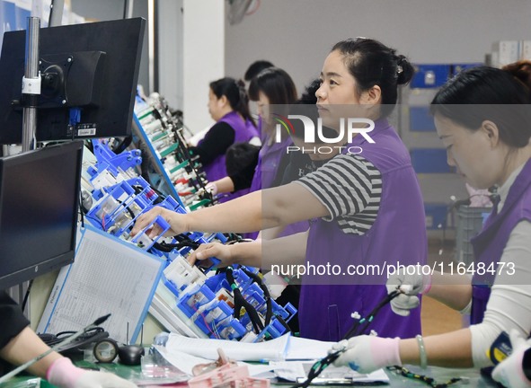 Workers work on a car harness production line at Handan Yongxu Automotive Electronics Co LTD in an industrial park in Yongnian district of H...