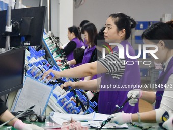 Workers work on a car harness production line at Handan Yongxu Automotive Electronics Co LTD in an industrial park in Yongnian district of H...