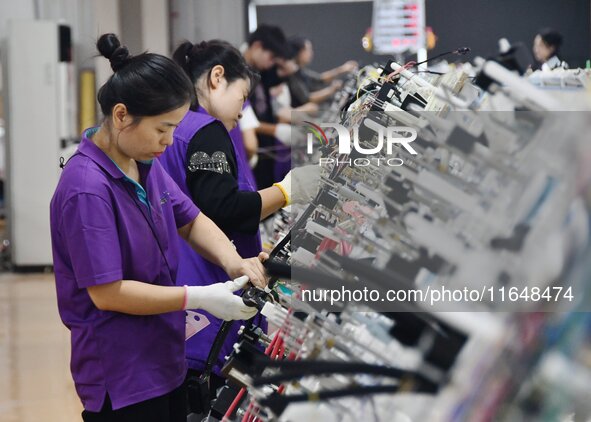 Workers work on a car harness production line at Handan Yongxu Automotive Electronics Co LTD in an industrial park in Yongnian district of H...