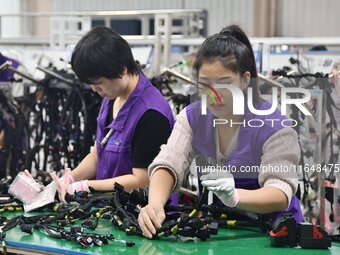 Workers work on a car harness production line at Handan Yongxu Automotive Electronics Co LTD in an industrial park in Yongnian district of H...