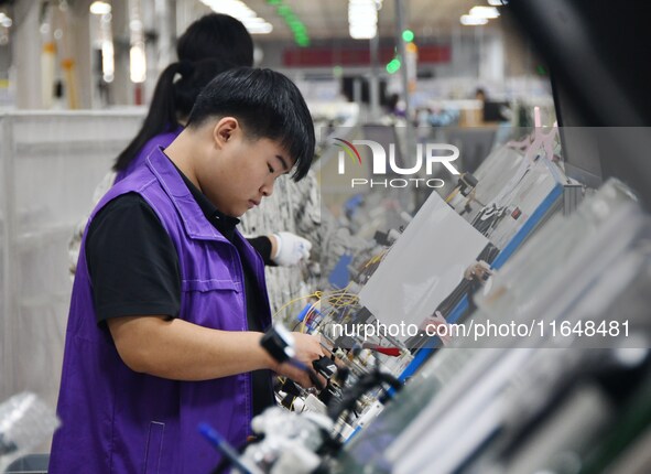 Workers work on a car harness production line at Handan Yongxu Automotive Electronics Co LTD in an industrial park in Yongnian district of H...