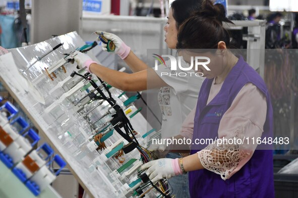 Workers work on a car harness production line at Handan Yongxu Automotive Electronics Co LTD in an industrial park in Yongnian district of H...