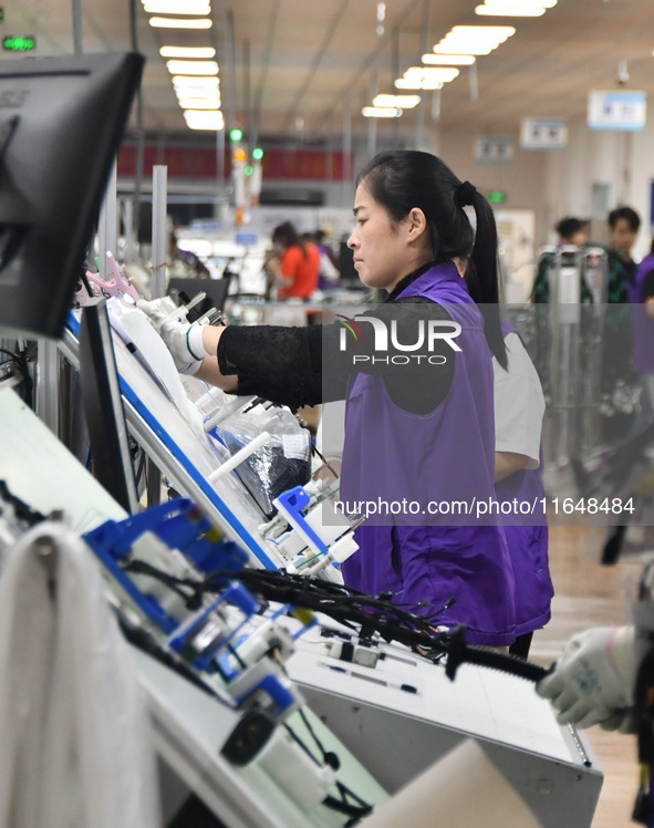 Workers work on a car harness production line at Handan Yongxu Automotive Electronics Co LTD in an industrial park in Yongnian district of H...