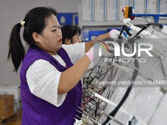 Workers work on a car harness production line at Handan Yongxu Automotive Electronics Co LTD in an industrial park in Yongnian district of H...