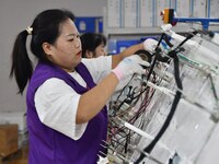 Workers work on a car harness production line at Handan Yongxu Automotive Electronics Co LTD in an industrial park in Yongnian district of H...