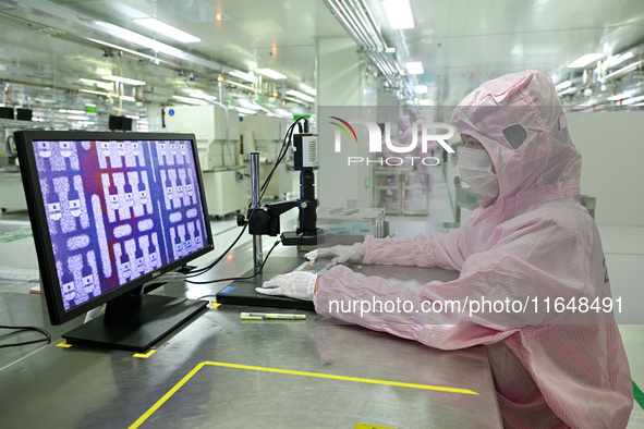 A worker works on an electronic component production line at Jiangsu Baopulai Semiconductor Co LTD in the Siyang Economic Development Zone i...