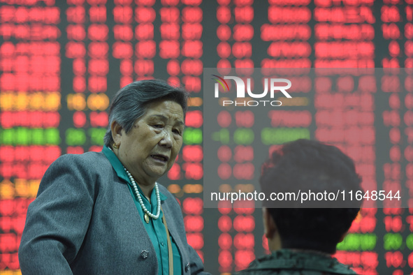 A customer pays attention to the stock market at a stock exchange in Hangzhou, China, on October 8, 2024. 