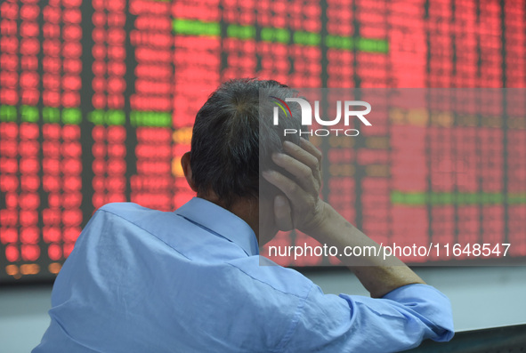 A customer pays attention to the stock market at a stock exchange in Hangzhou, China, on October 8, 2024. 