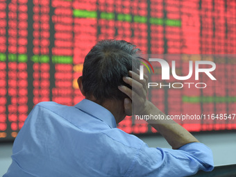 A customer pays attention to the stock market at a stock exchange in Hangzhou, China, on October 8, 2024. (