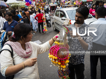 A woman buys decorative items at a street market ahead of the Durga Puja festival in Guwahati, India, on October 7, 2024. Shopping ahead of...