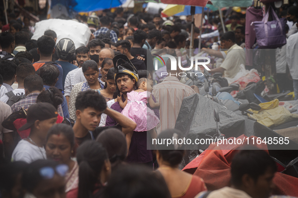 A person with his child is in the crowd of people shopping at a street market ahead of the Durga Puja festival in Guwahati, India, on Octobe...