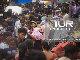 A person with his child is in the crowd of people shopping at a street market ahead of the Durga Puja festival in Guwahati, India, on Octobe...