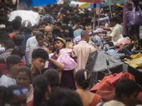 A person with his child is in the crowd of people shopping at a street market ahead of the Durga Puja festival in Guwahati, India, on Octobe...