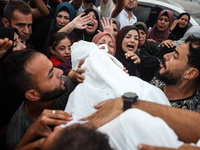 Palestinians mourn their relatives who are killed in overnight Israeli airstrikes on the Al-Bureij refugee camp in central Gaza at the Al-Aq...