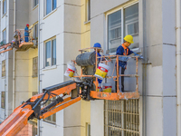 Workers paint the exterior walls of an old residential area at the renovation site in Suqian, Jiangsu province, China, on October 8, 2024. (