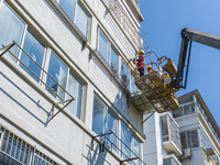 Workers paint the exterior walls of an old residential area at the renovation site in Suqian, Jiangsu province, China, on October 8, 2024. (