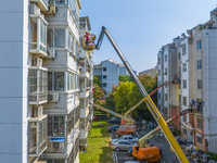 Workers paint the exterior walls of an old residential area at the renovation site in Suqian, Jiangsu province, China, on October 8, 2024. (