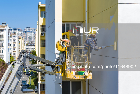 Workers paint the exterior walls of an old residential area at the renovation site in Suqian, Jiangsu province, China, on October 8, 2024. 