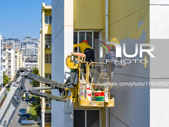 Workers paint the exterior walls of an old residential area at the renovation site in Suqian, Jiangsu province, China, on October 8, 2024. (