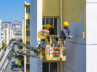 Workers paint the exterior walls of an old residential area at the renovation site in Suqian, Jiangsu province, China, on October 8, 2024. (