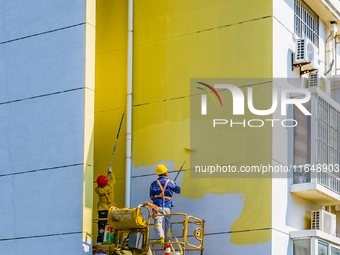 Workers paint the exterior walls of an old residential area at the renovation site in Suqian, Jiangsu province, China, on October 8, 2024. (