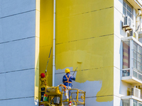 Workers paint the exterior walls of an old residential area at the renovation site in Suqian, Jiangsu province, China, on October 8, 2024. (