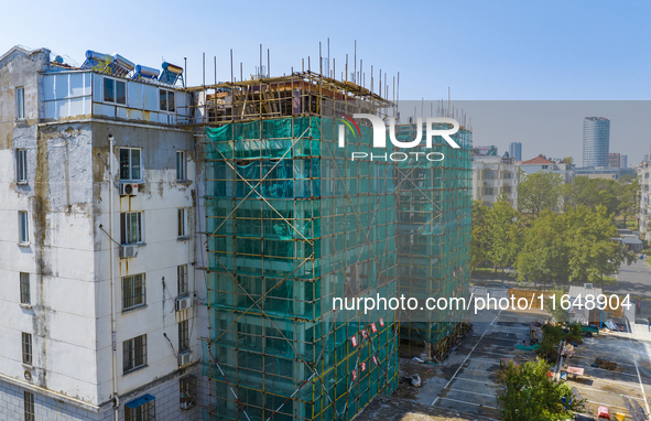 Workers install elevators for multi-storey buildings at the renovation site of an old residential area in Suqian, Jiangsu province, China, o...