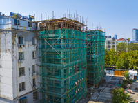 Workers install elevators for multi-storey buildings at the renovation site of an old residential area in Suqian, Jiangsu province, China, o...