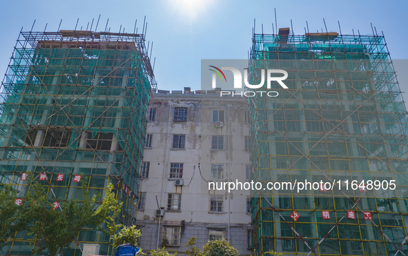 Workers install elevators for multi-storey buildings at the renovation site of an old residential area in Suqian, Jiangsu province, China, o...